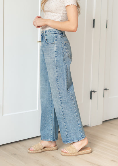 Side view of medium wash barrel jeans paired with woven slide sandals
