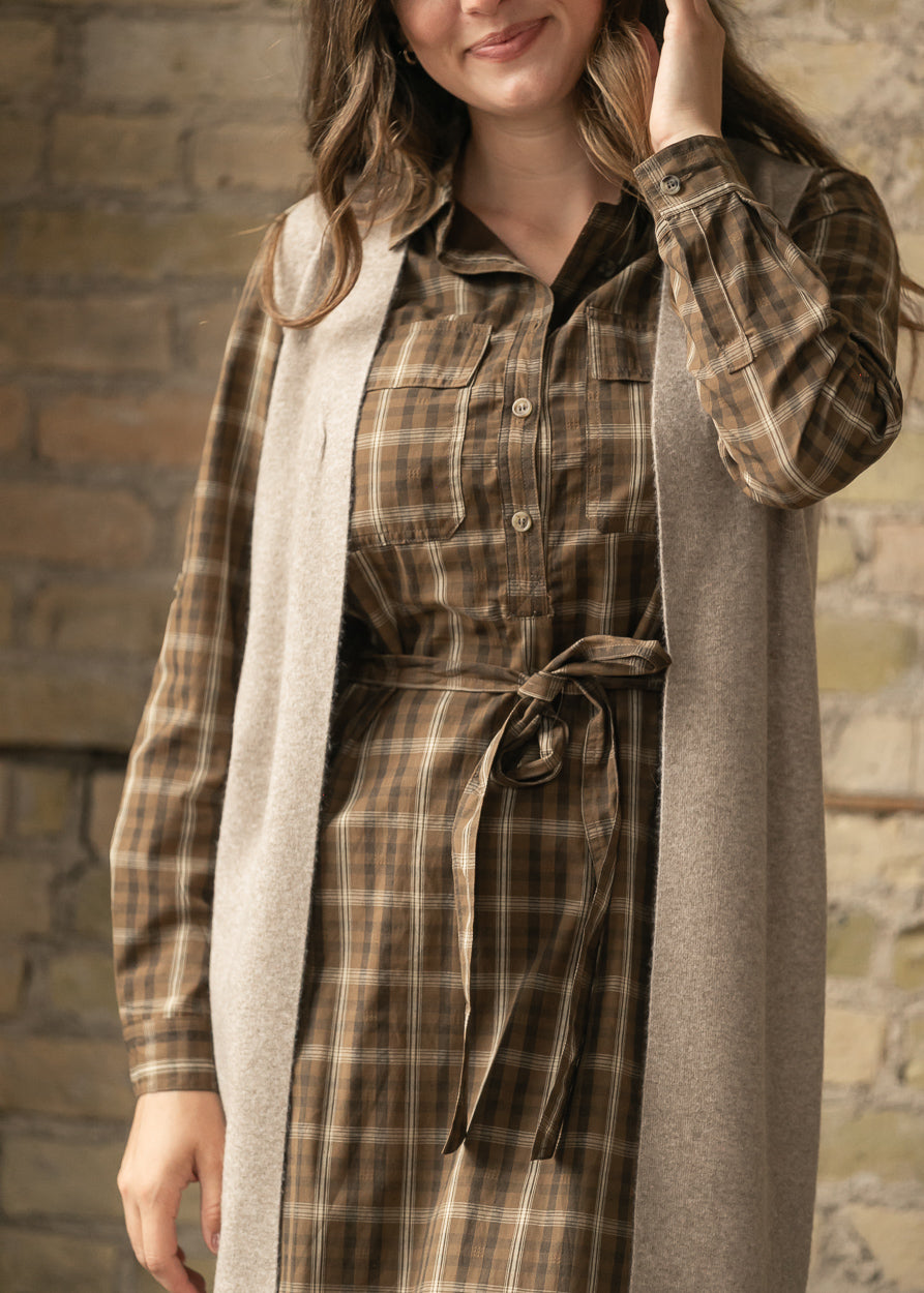 Close-up of the brown plaid cotton dress showing the functional button front and self-tie waist.
