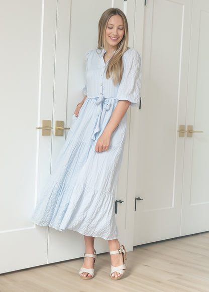 Light blue waist tie maxi dress with tiered skirt and balloon sleeves, styled with cream heeled sandals.