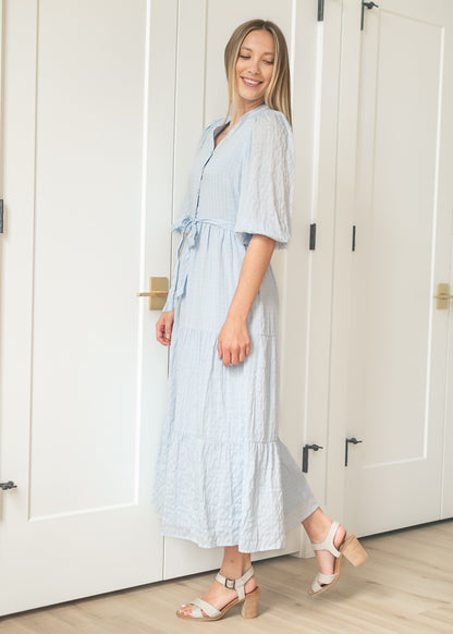 Side view of light blue tiered maxi dress with balloon sleeves and flowing maxi length.