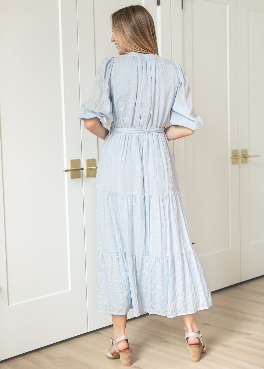 Back view of light blue tiered maxi dress showing gathered waist and three-tier skirt.