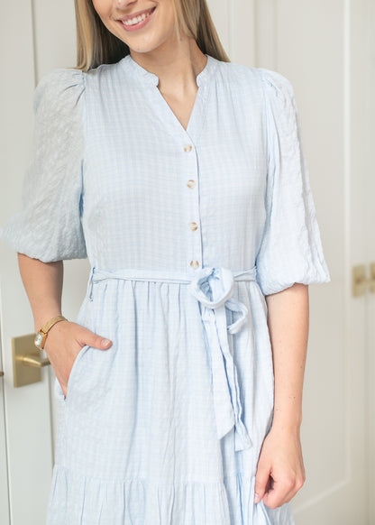 Close-up of light blue maxi dress side pocket and self-tie waist over a textured woven bodice.