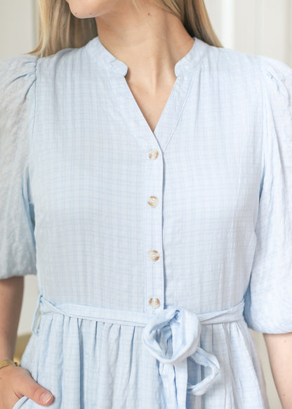 Close-up of light blue maxi dress neckline showing split collar, horn-look buttons, and self-tie waist.
