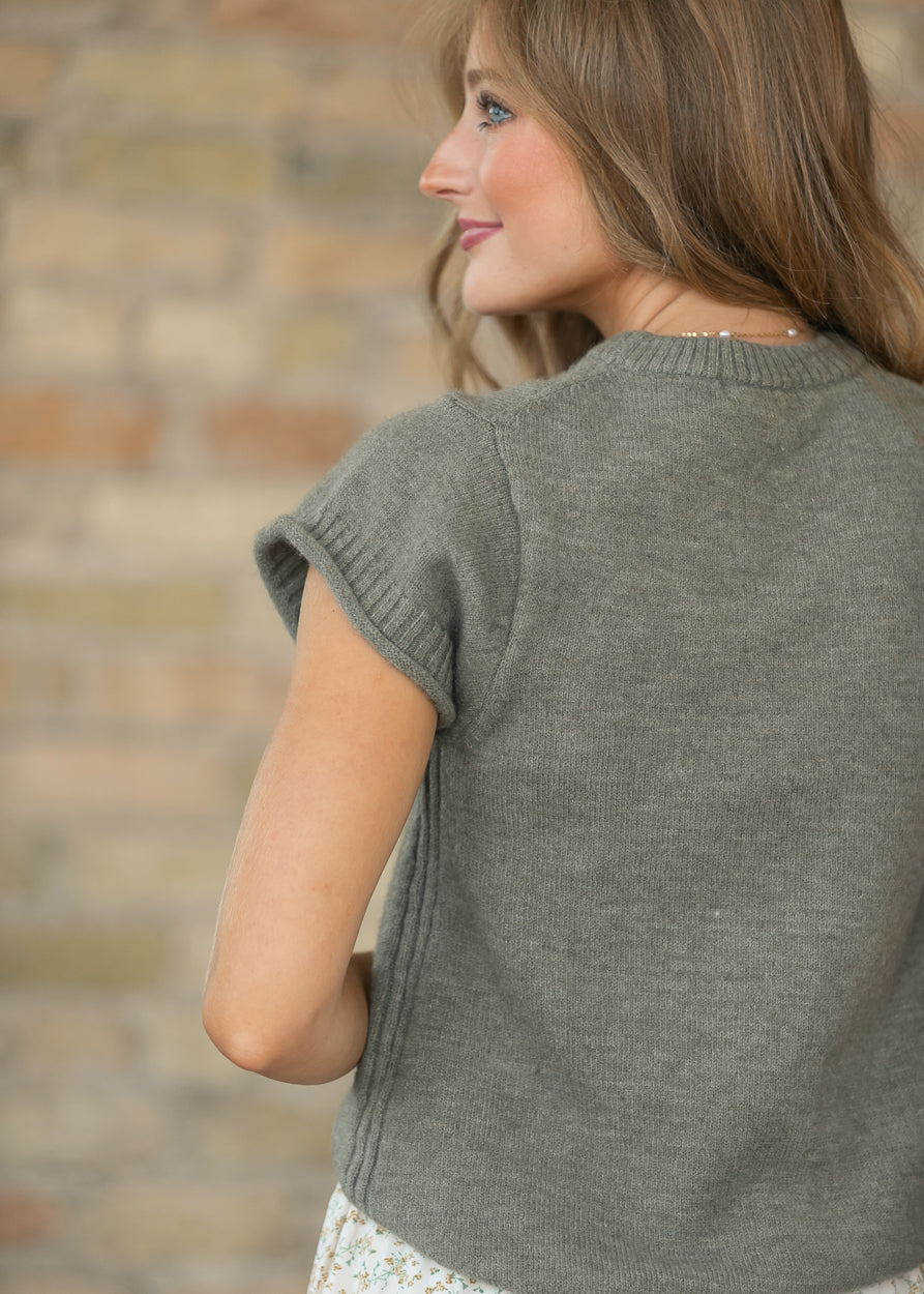 Back of light olive sweater T-shirt showing the simple knit construction and rolled sleeve.