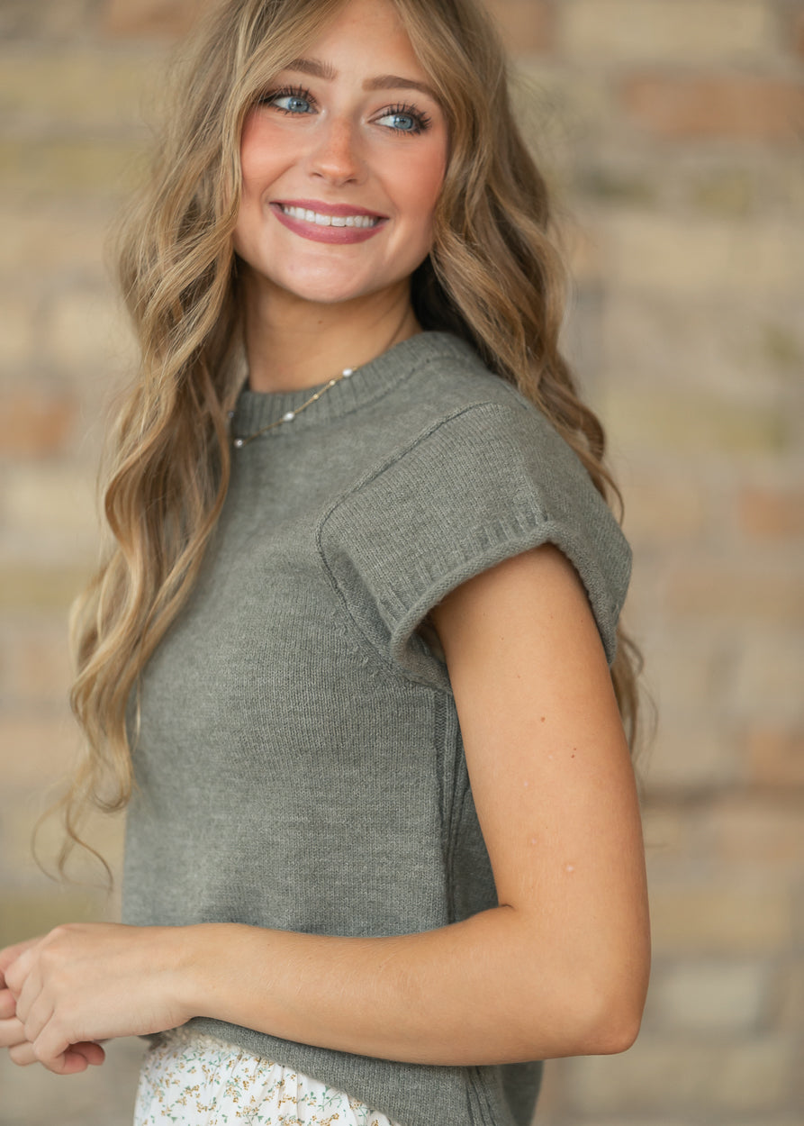 Close-up of light olive sweater T-shirt showing the crew neckline, soft knit texture, and rolled sleeve.