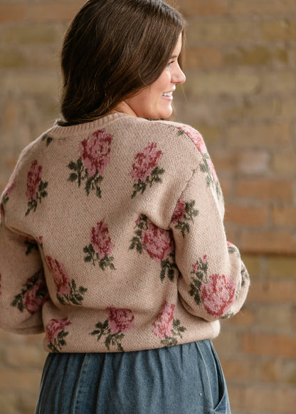 Close-up of the sand sweater's back showing pink rose motifs, green leaves, and knit texture.