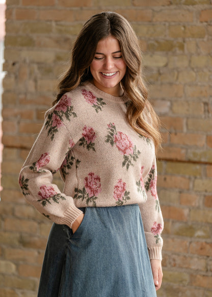 Sand floral sweater showing its crew neckline and ribbed cuffs, with the model's hand in a denim skirt pocket.