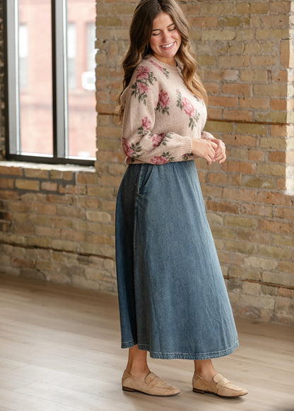 Side of sand floral long sleeve sweater showing ribbed cuffs, styled with a denim skirt and tan flats.