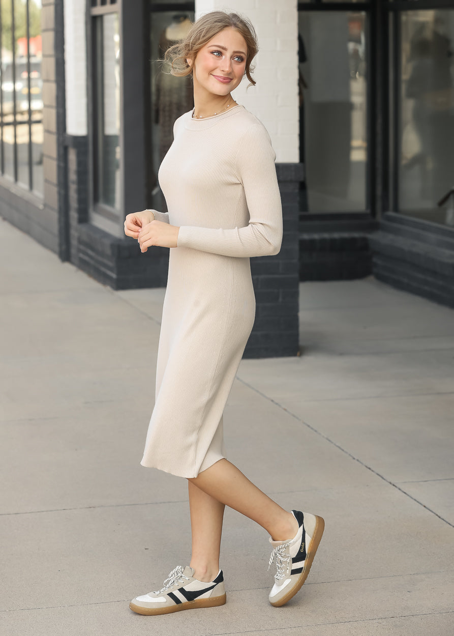 Taupe Mayra ribbed midi dress with long sleeves and fitted silhouette, styled with neutral sneakers.