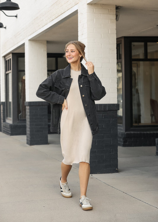 Taupe Mayra midi dress layered under an oversized black denim jacket with neutral sneakers.