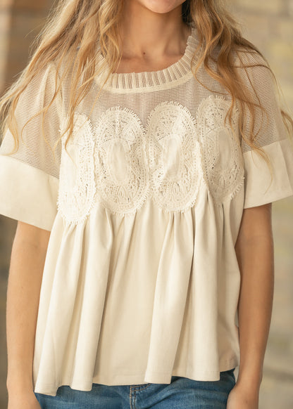 Close-up of cream mesh yoke and embroidered lace detailing across the front of the top.