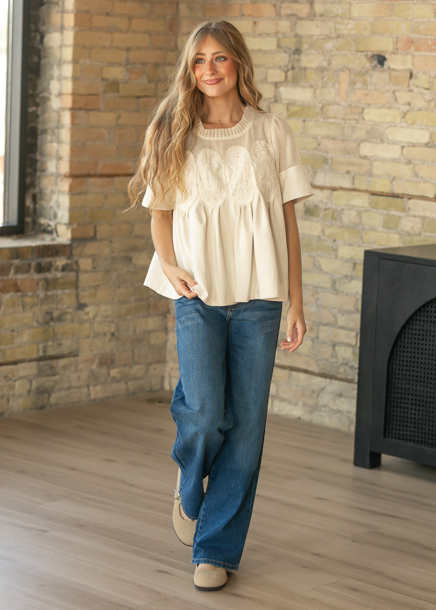 Cream mesh lace top styled with wide-leg denim and neutral flats.