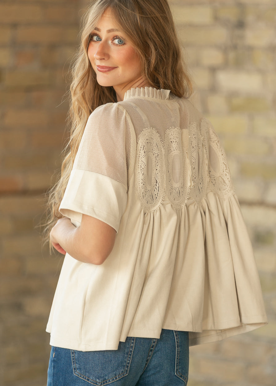 Back of cream mesh lace top showing sheer mesh yoke, lace accents, and loose gathered silhouette.