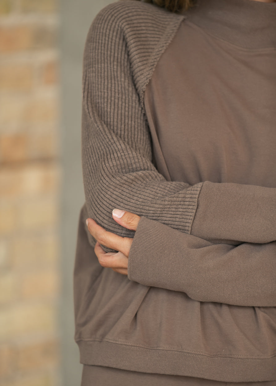 Close-up of mocha mock neck sweatshirt with textured long sleeves and extended ribbed cuffs.