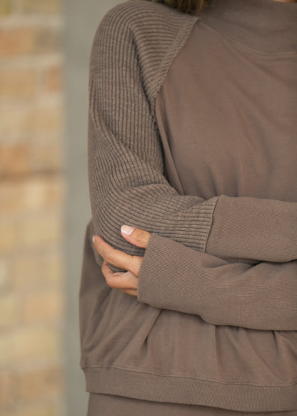 Close-up of mocha mock neck sweatshirt with textured long sleeves and extended ribbed cuffs.