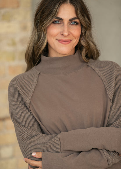 Close-up of mocha mock neck sweatshirt with textured long sleeves and extended ribbed cuffs.