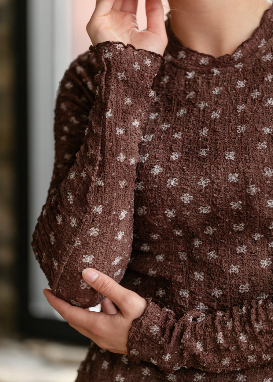 Brown floral long sleeve top with textured fabric, mock neckline, and delicate lettuce trim.