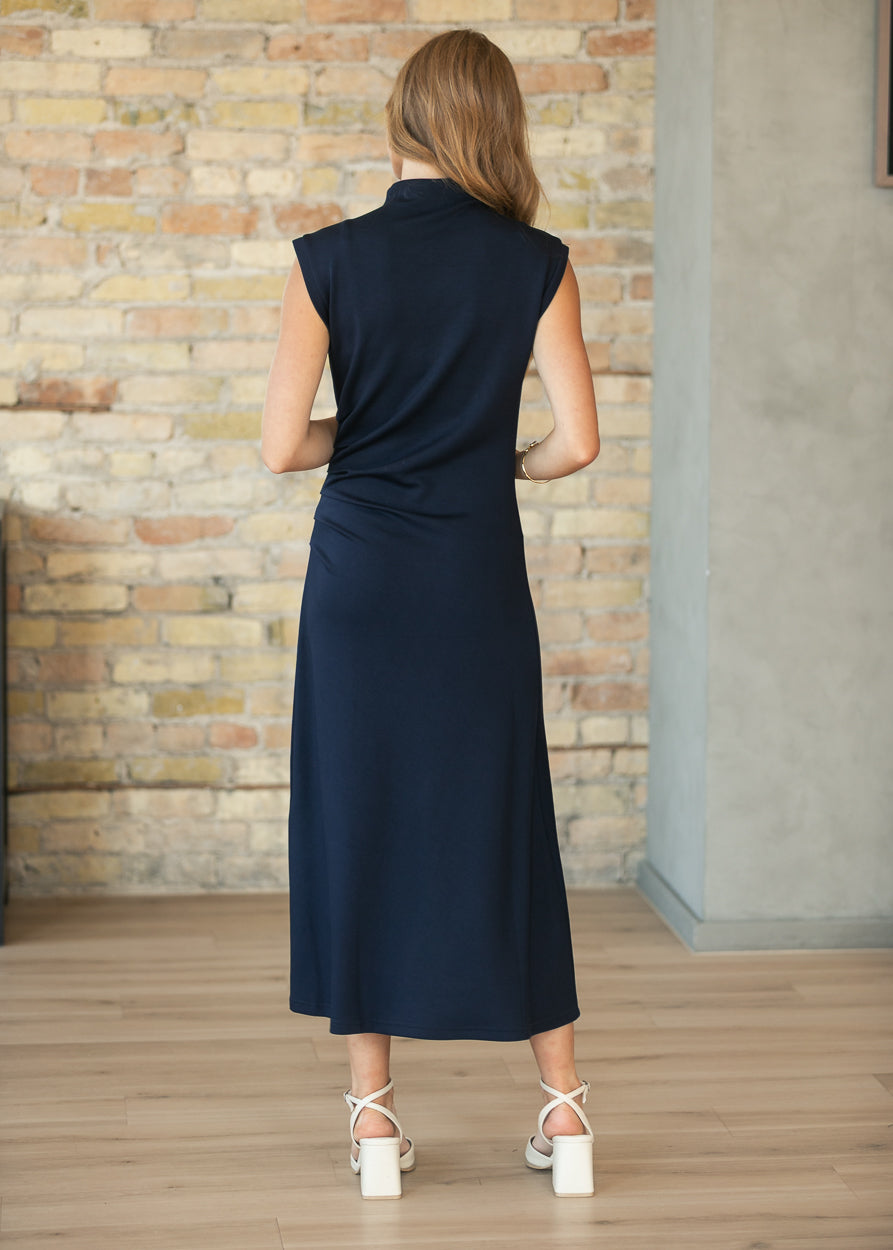 Back of navy mockneck midi dress showing the sleeveless cut and mid-calf hem.