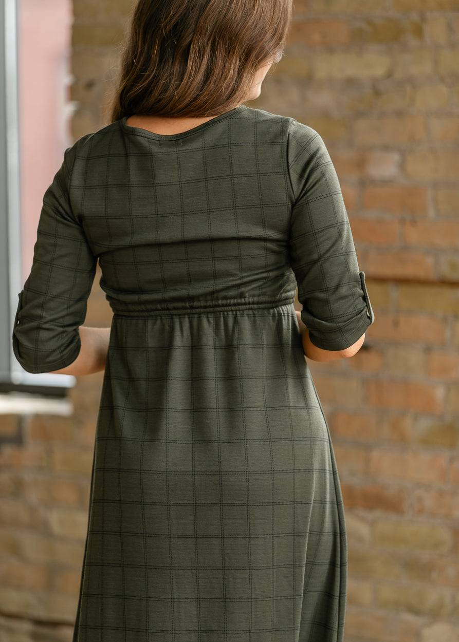 Back of olive windowpane dress showing a rounded neckline, gathered waist, and rolled sleeves.