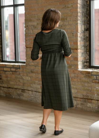 Back of olive windowpane dress showing a rounded neckline, gathered waist, and rolled sleeves.