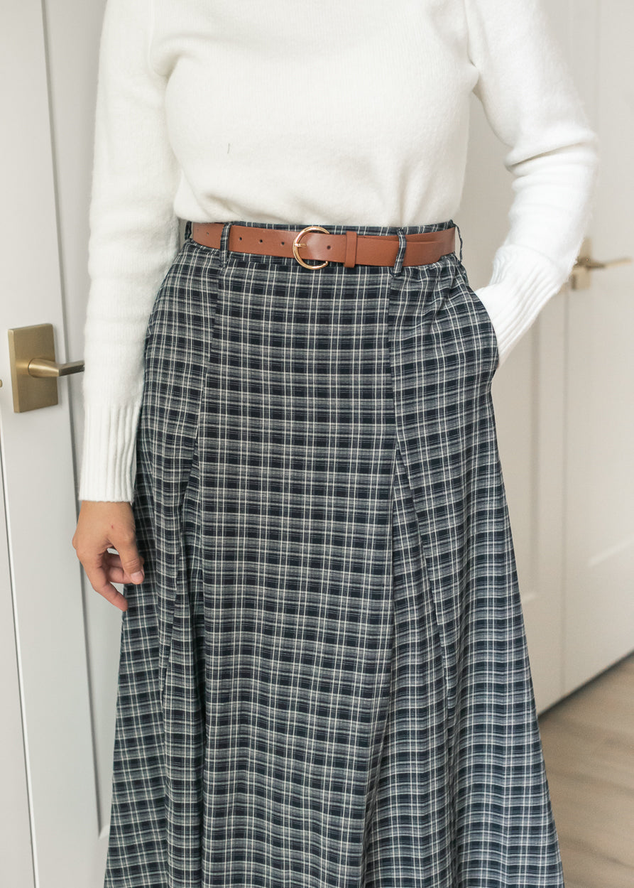 Close-up of navy plaid maxi skirt showing the belted waist, front pleating, and side pocket.
