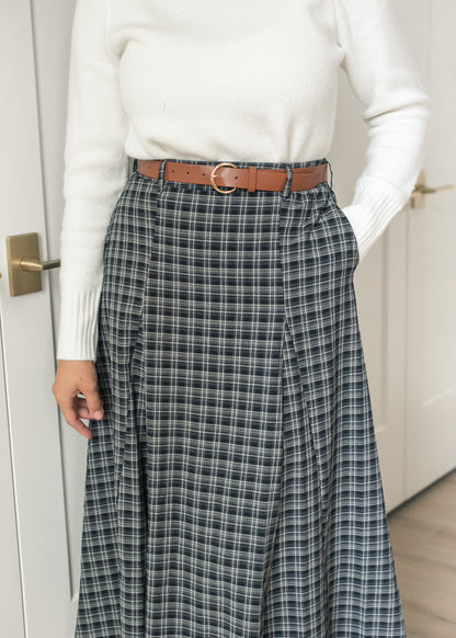 Close-up of navy plaid maxi skirt showing the belted waist, front pleating, and side pocket.