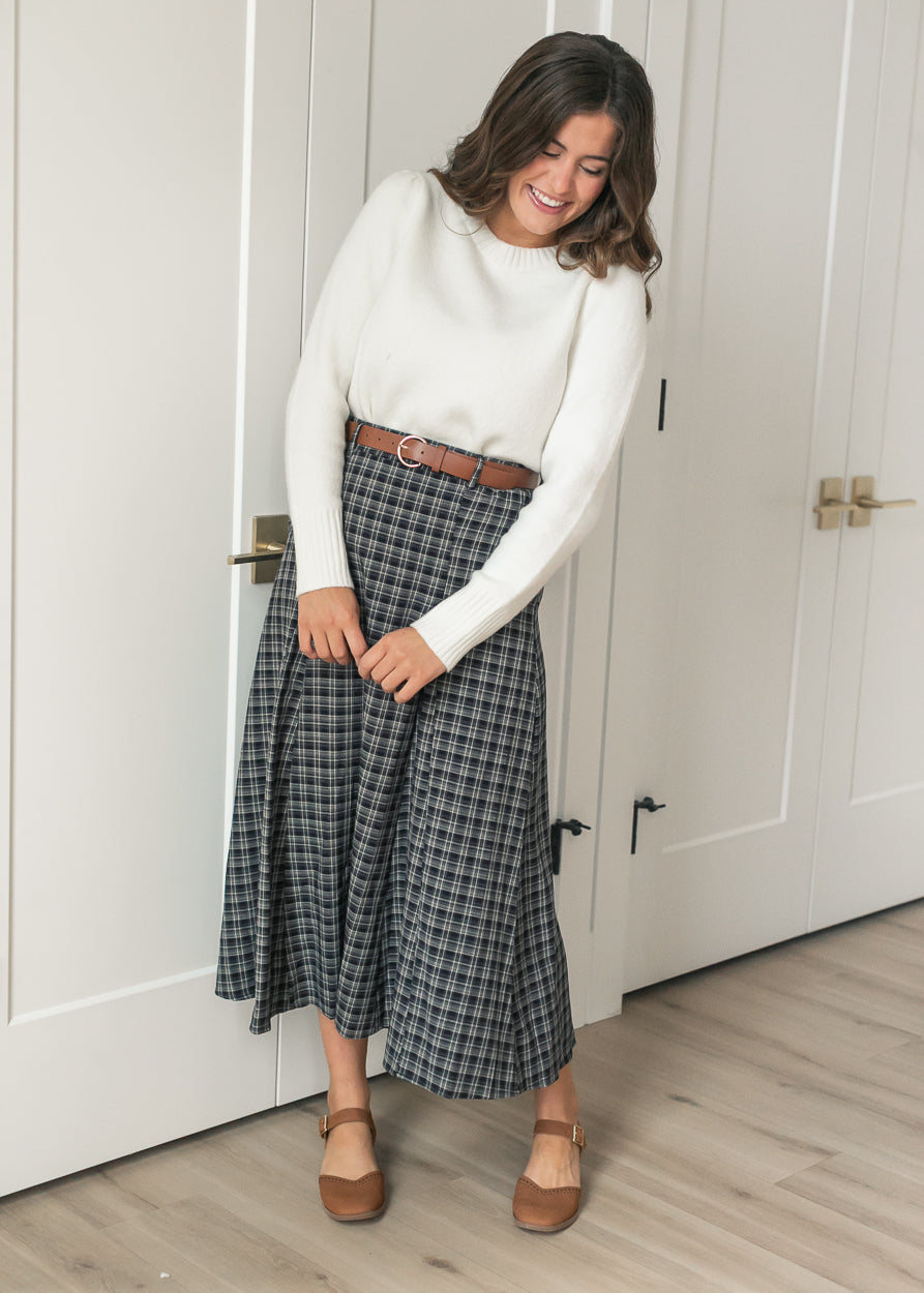 Full-length navy plaid flare maxi skirt with mid-shin hem, styled with an ivory sweater and brown flats.