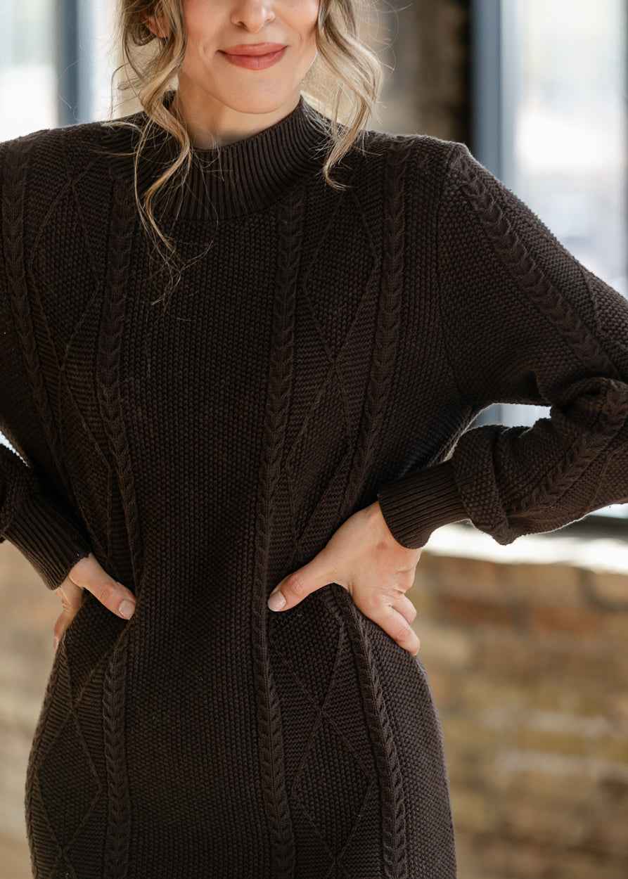 Close-up of chocolate brown sweater dress showing cable knit texture, diamond stitching, and ribbed mock neckline.