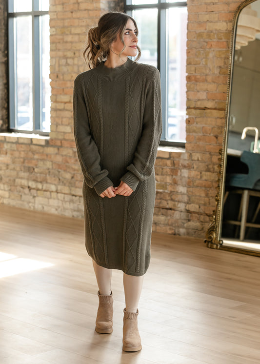 Noelle Olive Sweater Midi Dress featuring cable knit detailing, long sleeves, and a mock neckline with tan ankle boots.