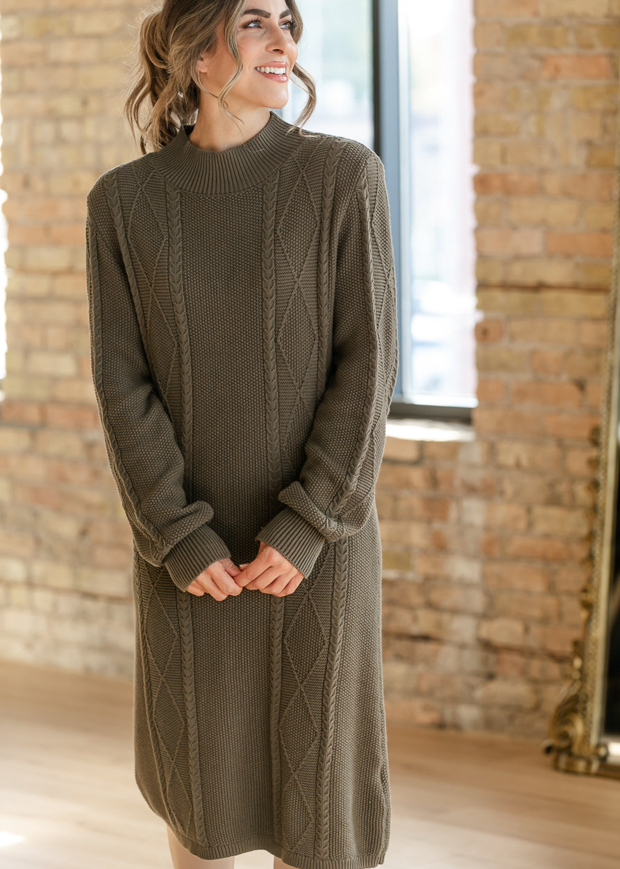 Close-up of olive cable knit sweater dress highlighting the mock neckline, textured stitching, and ribbed cuffs.