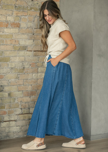 Paneled denim maxi skirt with drawstring waist and side pockets, styled with an oatmeal sweater tee.