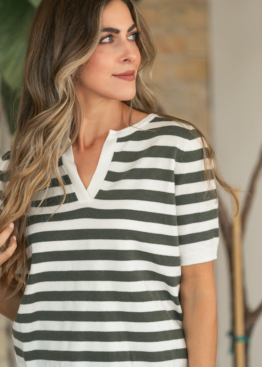 Close-up of the notch v-neckline on an olive and ivory striped sweater top.