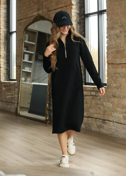 Black Olympia quarter-zip sweatshirt with longline hem, side pockets, and white sneakers.