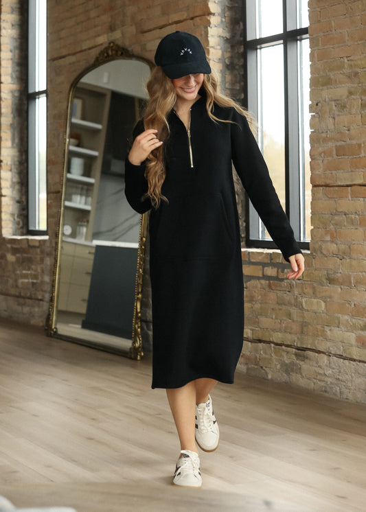 Black Olympia quarter-zip sweatshirt with longline hem, side pockets, and white sneakers.