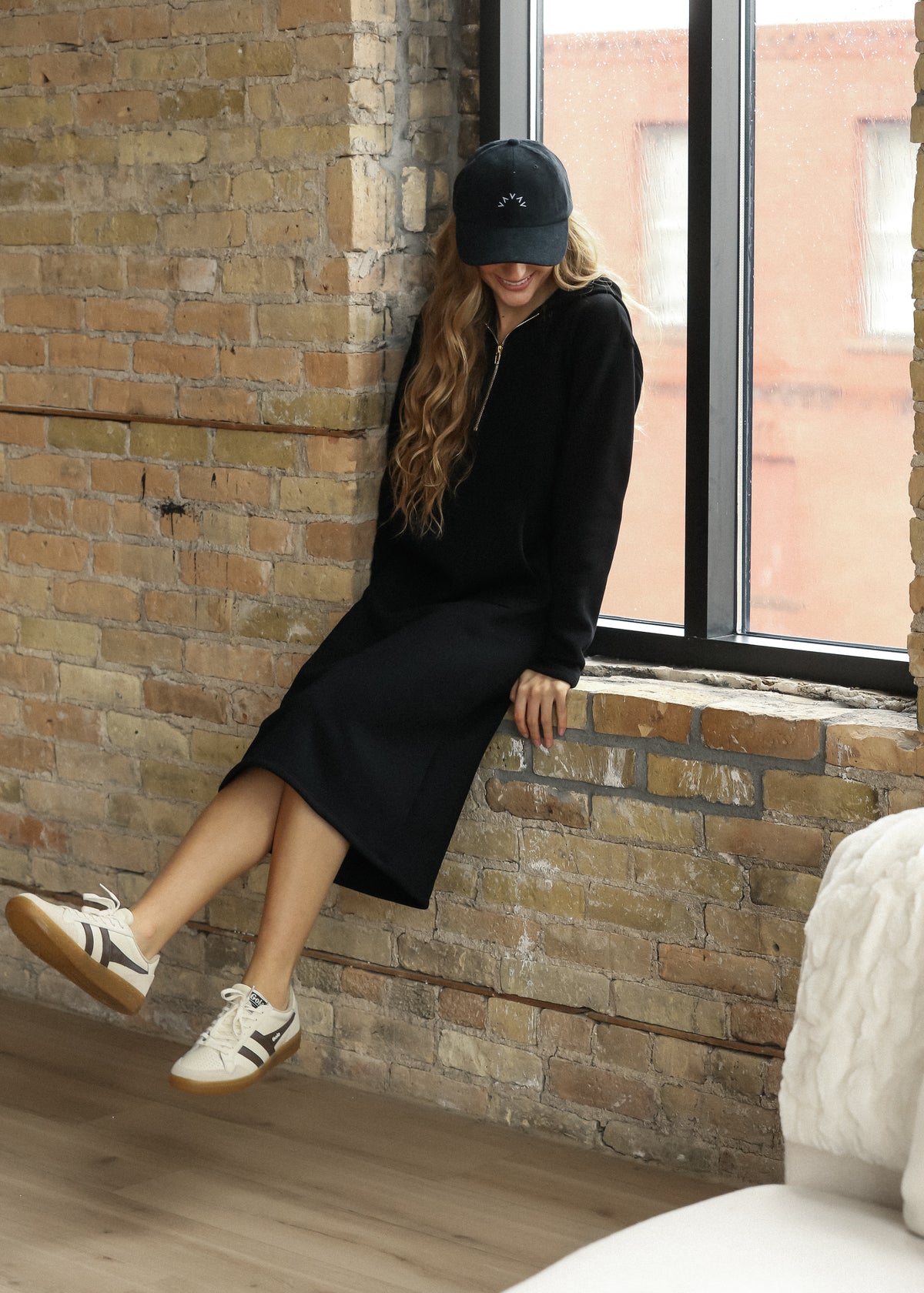 Full-length black Olympia sweatshirt with side pockets, styled with white sneakers.