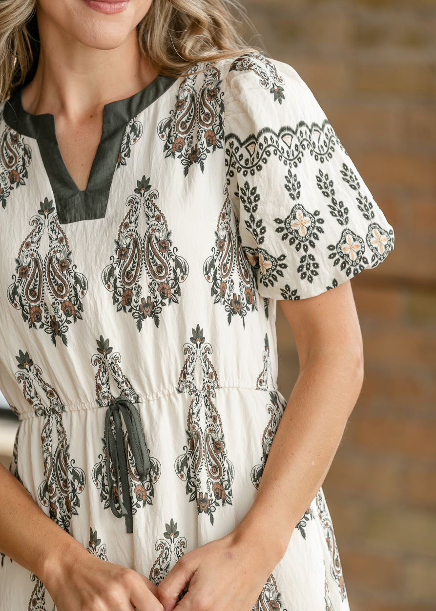 Close-up of olive contrast notch neckline and patterned puff sleeve on the ivory paisley midi dress.