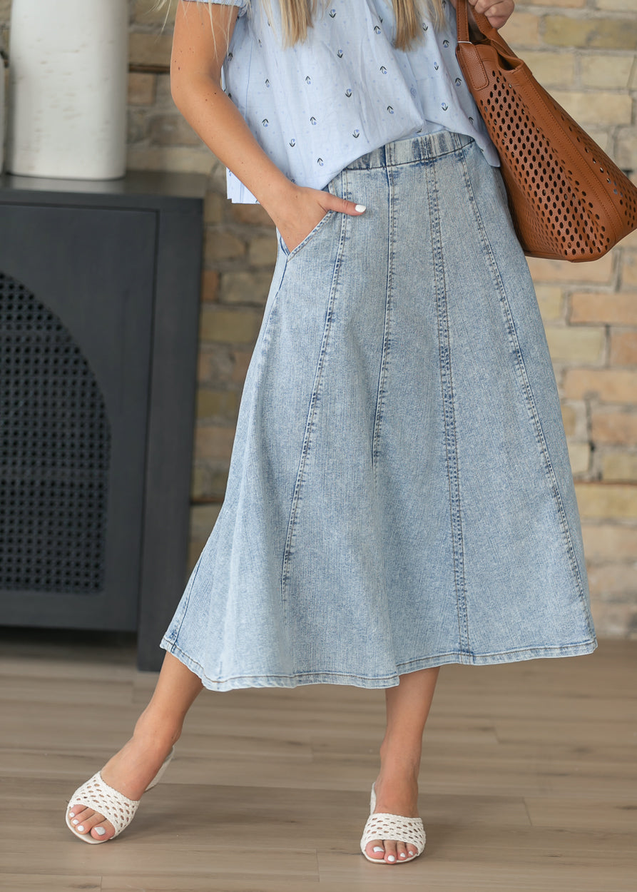 Paneled denim midi skirt with a flowing A-line silhouette and elastic waist.
