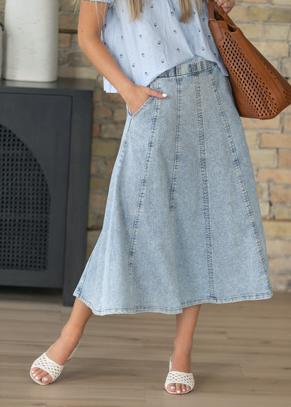 Paneled denim midi skirt with a flowing A-line silhouette and elastic waist.
