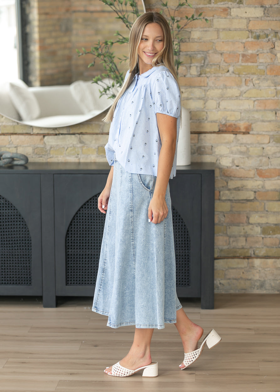 Side view of the light blue floral jacquard blouse showing the loose fit and short puff sleeves.