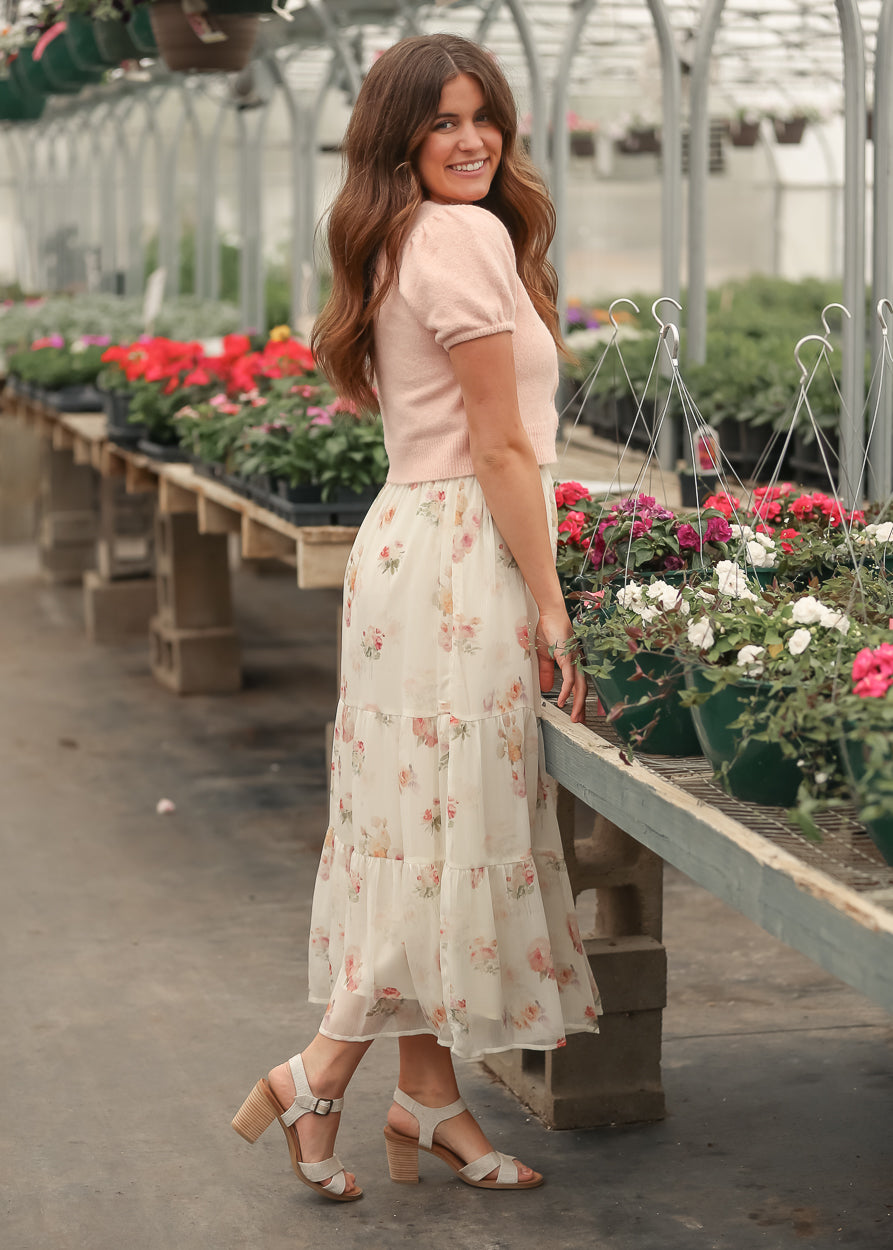 Side view of soft pink cropped cardigan showing puff sleeve detail and semi-fitted shape.