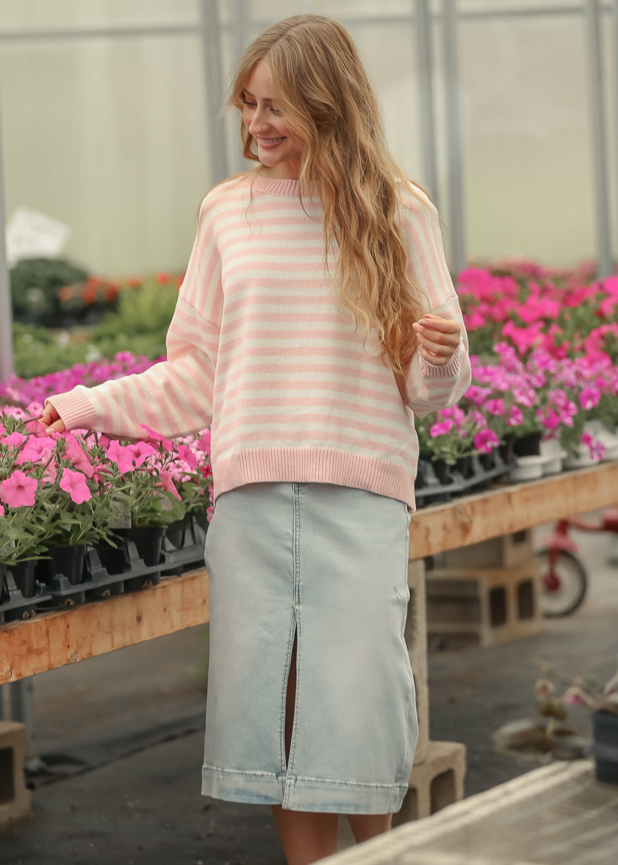 Pink and cream striped knit sweater styled with a light wash denim midi skirt in natural daylight.