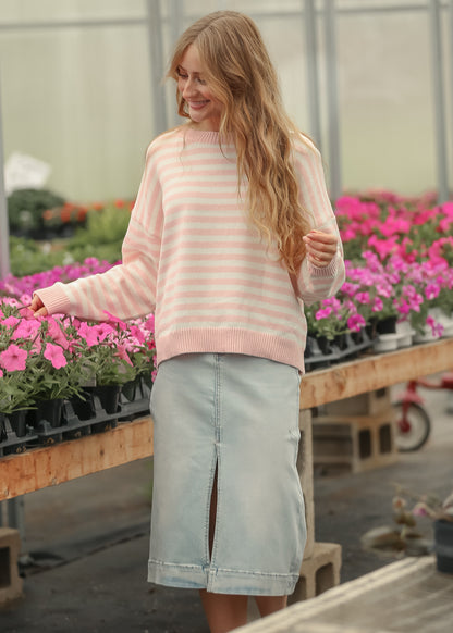 Pink and cream striped knit sweater styled with a light wash denim midi skirt in natural daylight.