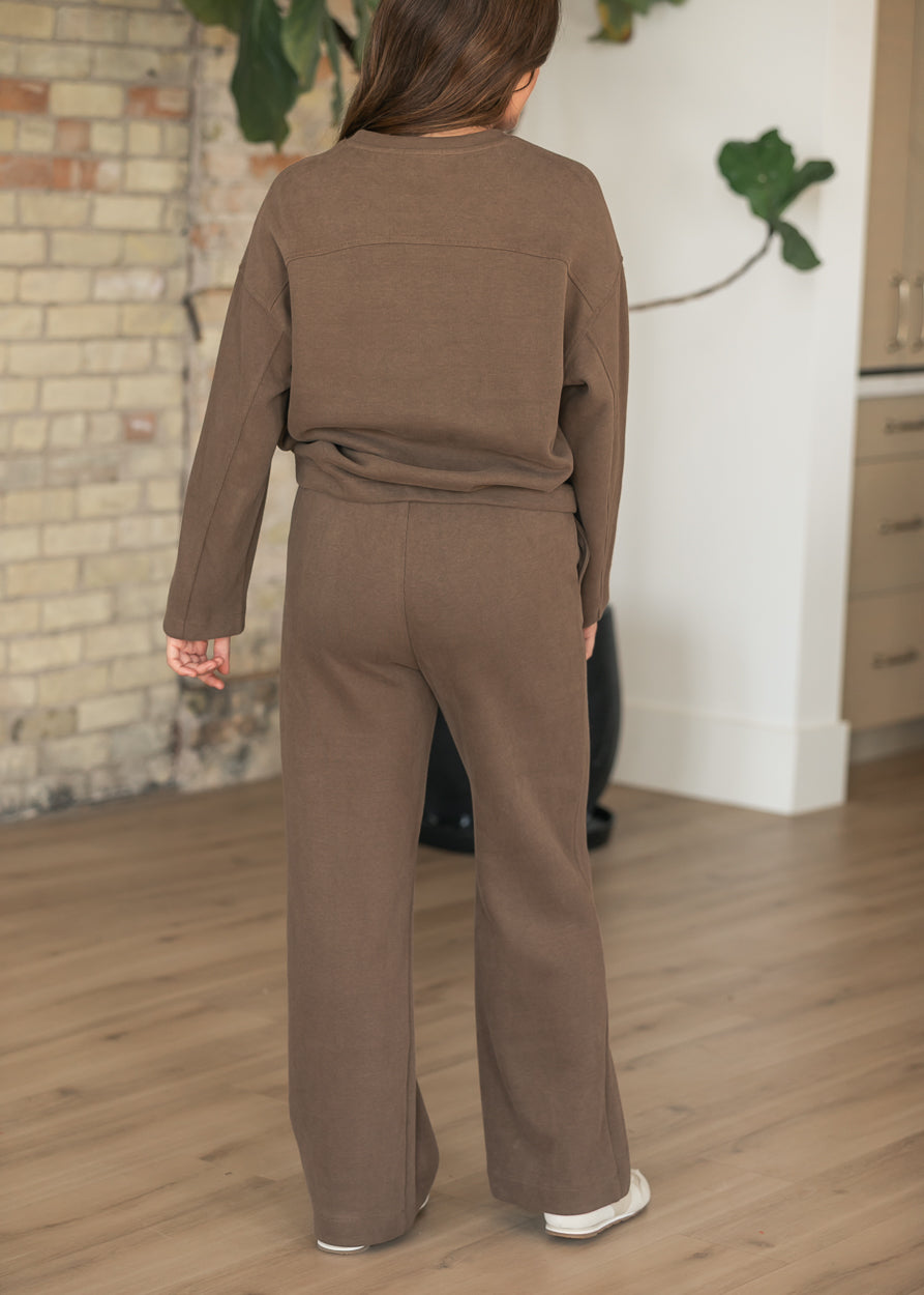 Back of brown wide leg jogger pants showing relaxed fit and full-length silhouette, styled with matching pullover.