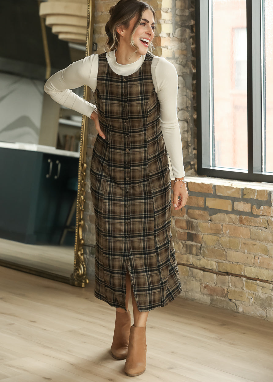 Brown plaid midi dress styled over an ivory long sleeve top with tan ankle boots.
