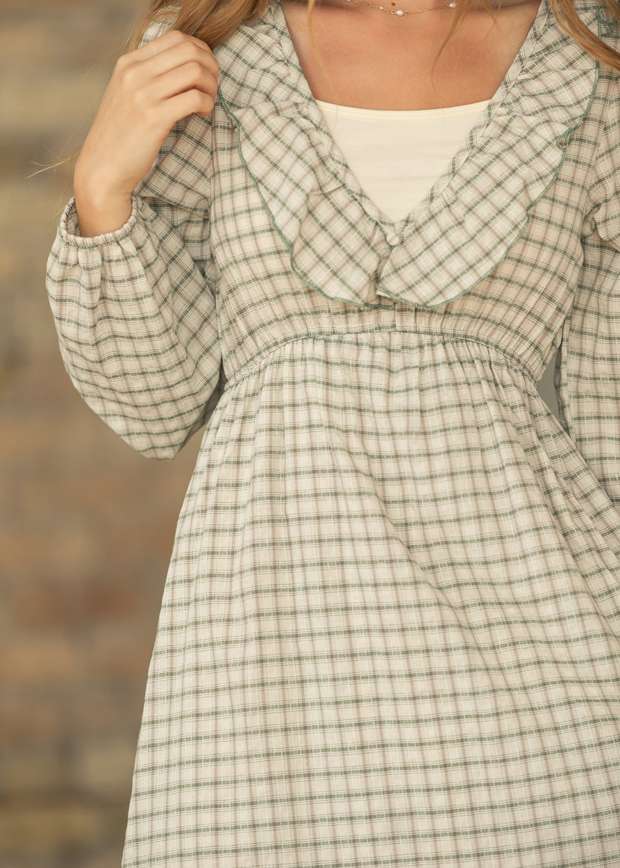 Close-up of cream and sage plaid dress showing the ruffled V-neckline, gathered waist, and elastic cuff.