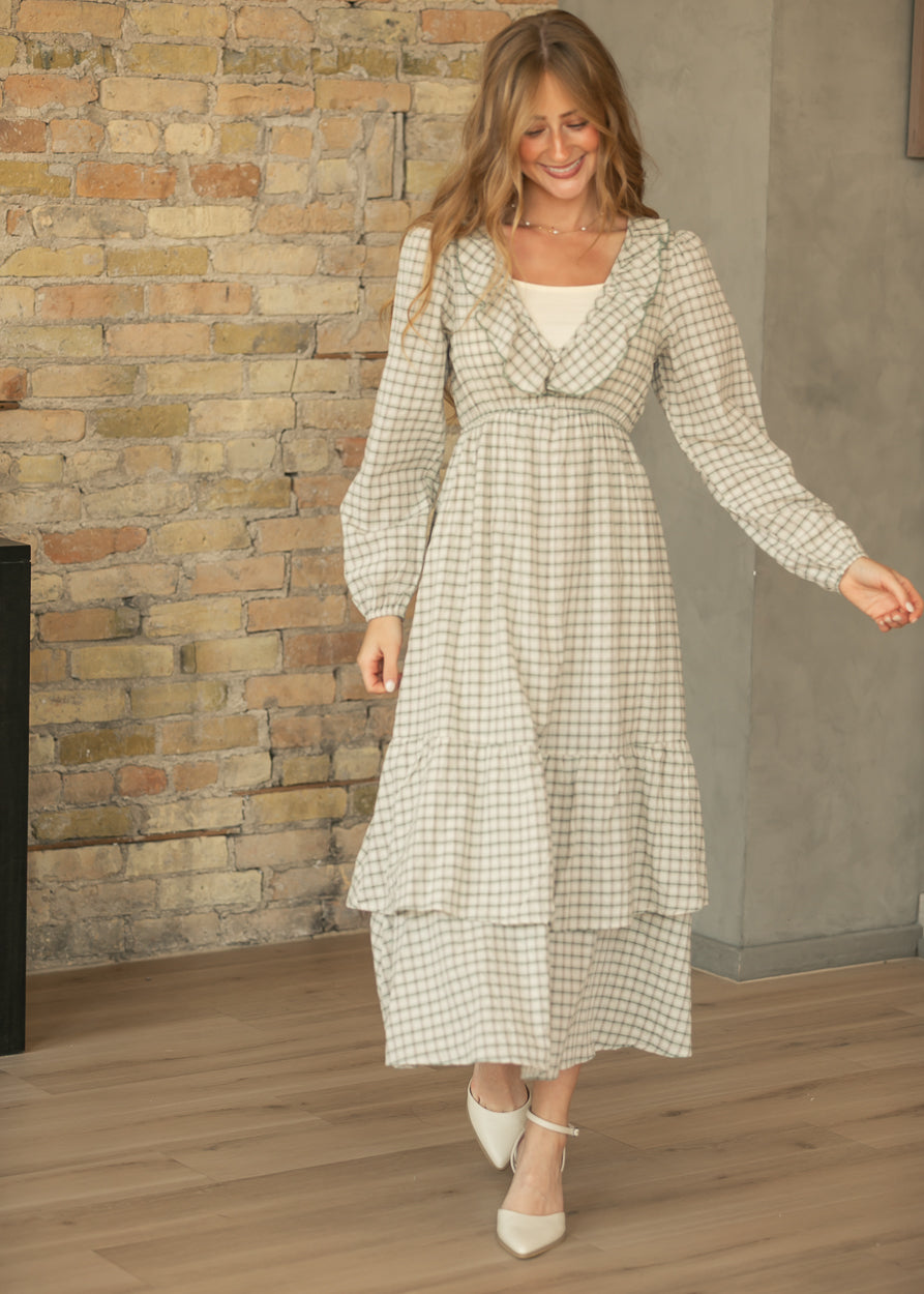 Cream and sage plaid midi dress with long sleeves and tiered skirt, styled with pointed-toe cream heels.