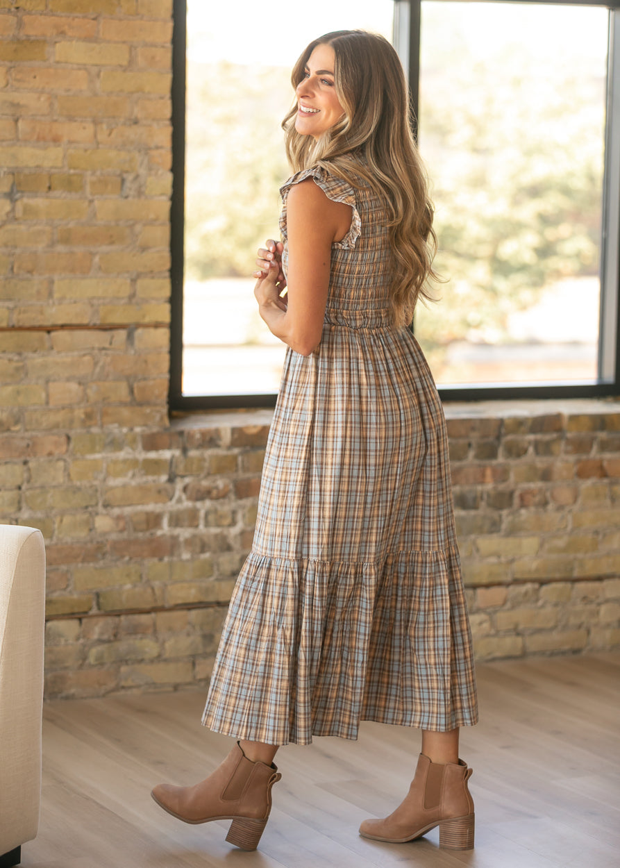 Plaid cotton maxi dress with a smocked waist and tiered skirt, styled with brown ankle boots.