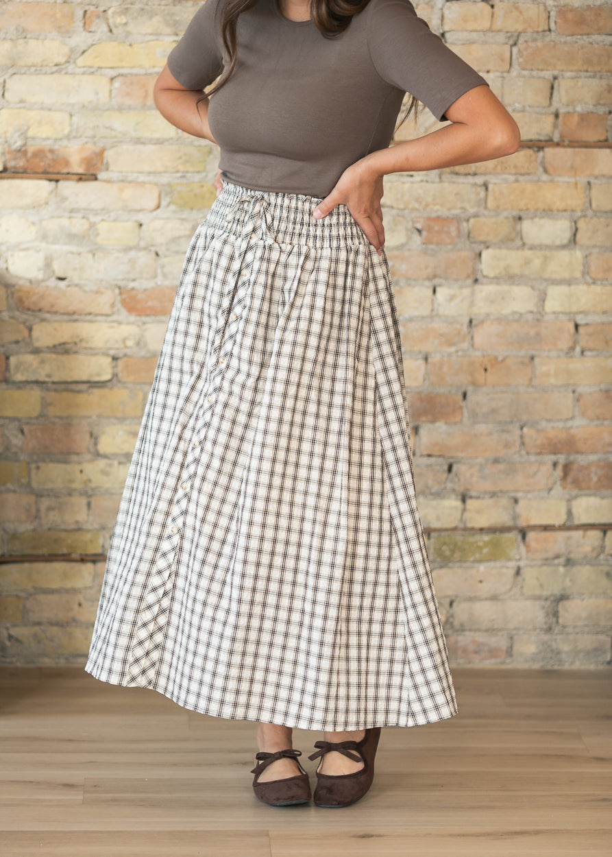 Cream and brown plaid midi skirt with smocked waist, styled with a fitted short sleeve top and flats.