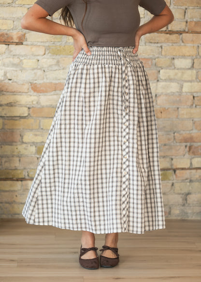 Cream plaid midi skirt with smocked waistband, decorative tie, and button-front detail.