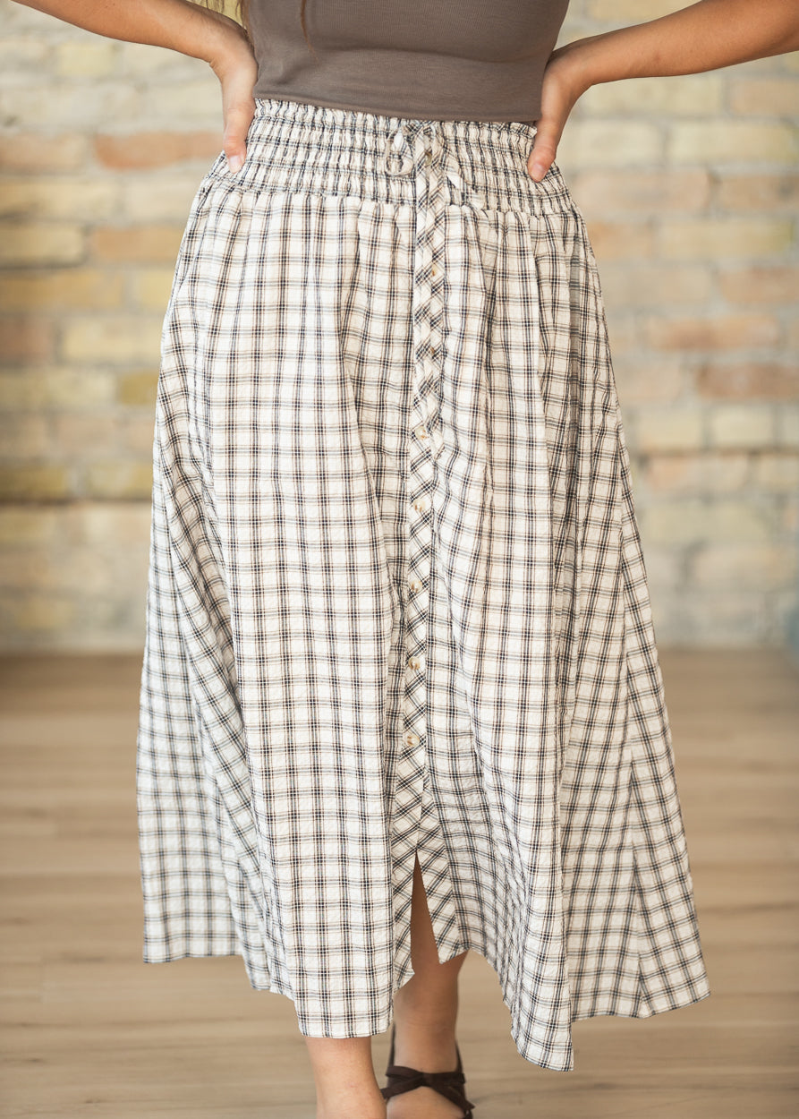 Cream plaid midi skirt with decorative button front and softly flowing A-line shape.